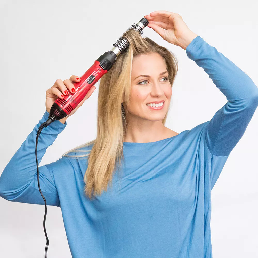 Woman using a red hair styling tool on her hair 